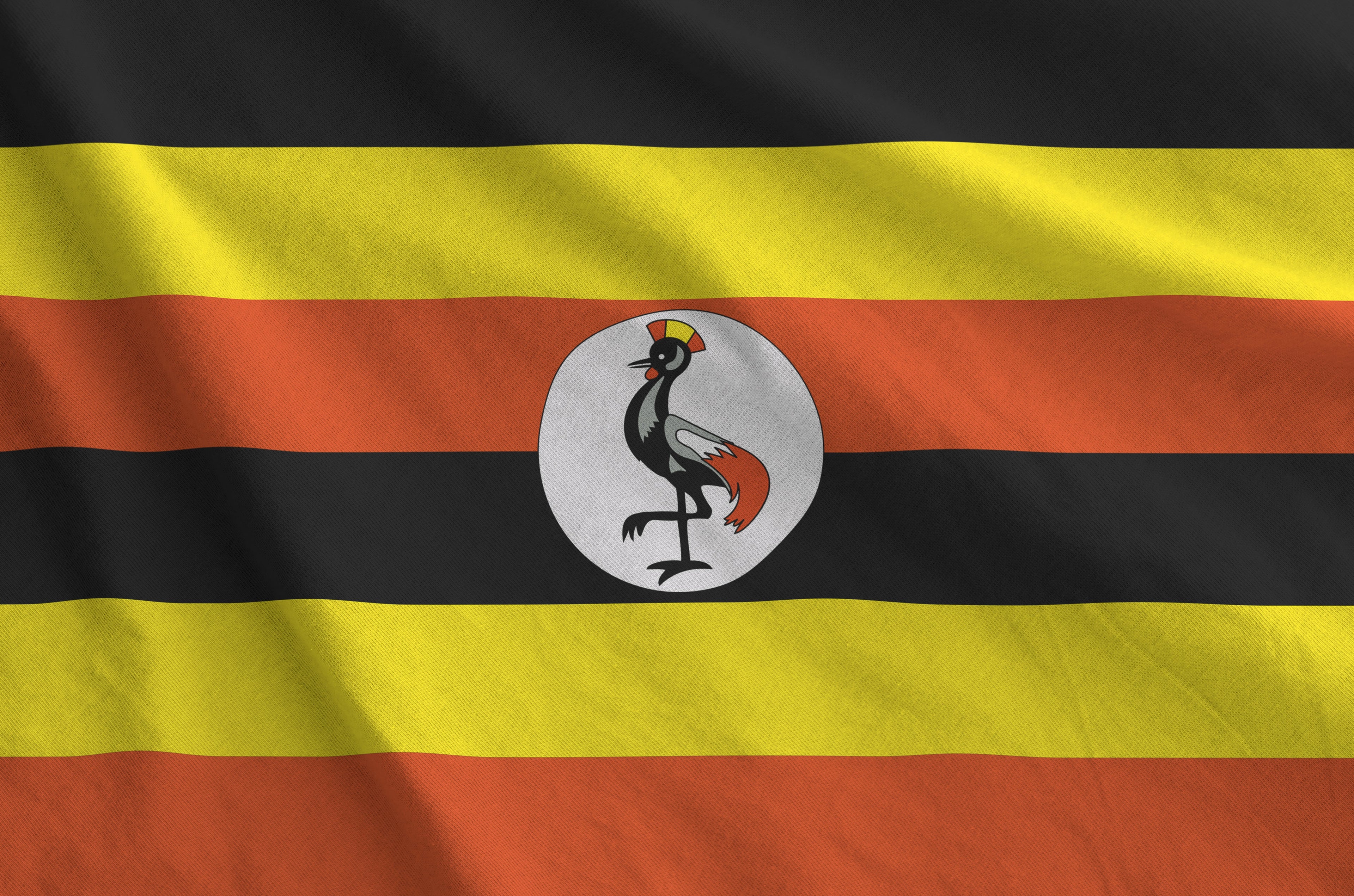 Flag of Uganda with black, yellow, and orange stripes and a central emblem